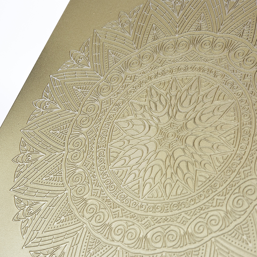 Detalle de un azulejo dorado con una mandala impresa en relieve, sin contraste de color